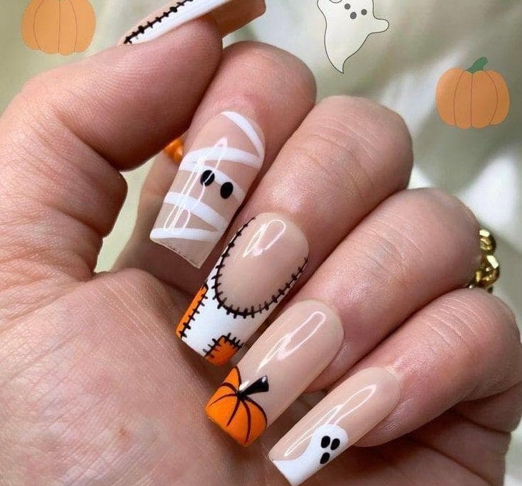 Halloween nails with mummy art, stitched details, pumpkin tips, and tiny ghost accents on nude square nails
