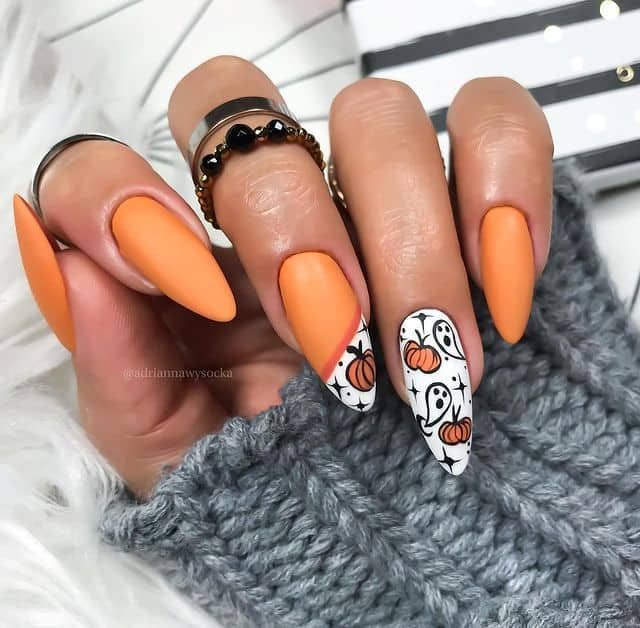Matte orange Halloween nails with ghost and pumpkin accent art on long almond nails
