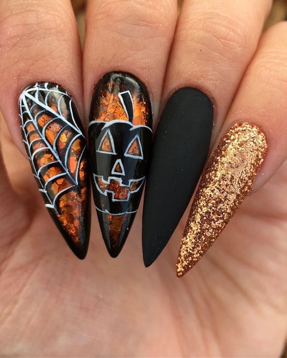 Black and orange Halloween stiletto nails with glitter, spider web art, and jack o lantern nail design