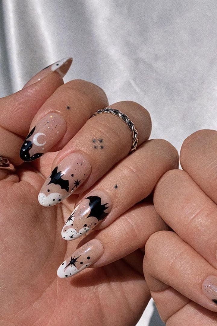Neutral Halloween nails with black bats, stars, moon accents, and white French tip details
