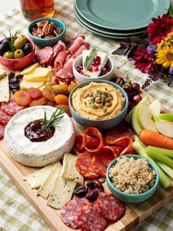 Fall charcuterie board with cheese, meats, hummus, fruit and vegetables