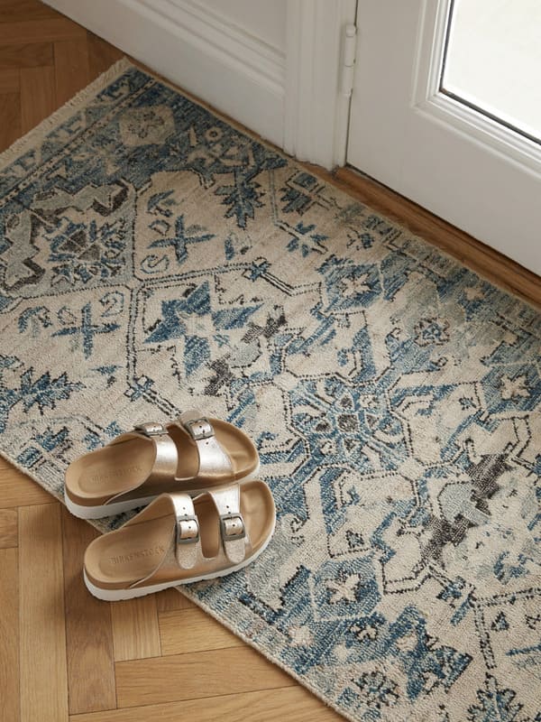 Indoor shoes sitting beside a rug near the front door