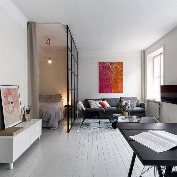 Studio apartment bedroom separated by a black framed glass divider