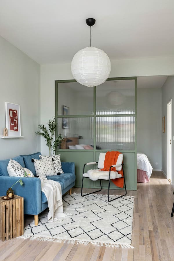 Studio apartment bedroom separated from the living area with a glass room divider