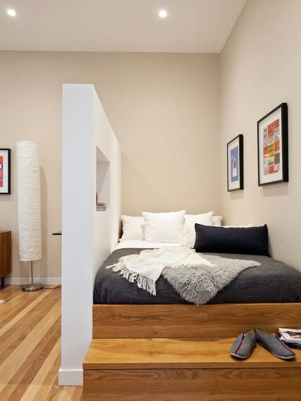 Raised studio apartment bed with a partial privacy wall
