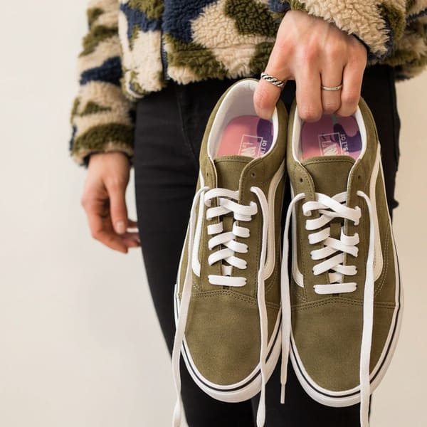 Person holding outdoor shoes after taking them off at home