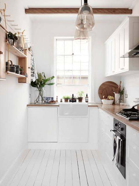Bright white galley kitchen with farmhouse sink, open shelves and wood countertops