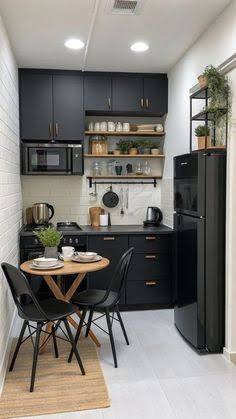 Compact black kitchen with folding dining table, open shelving and tall refrigerator