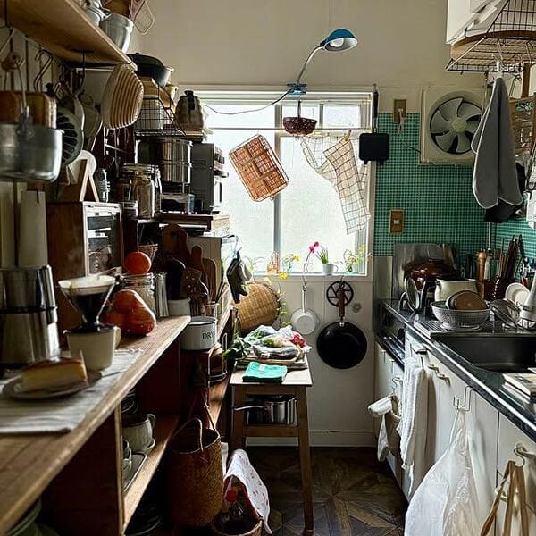 Narrow kitchen filled with hanging pots and crowded kitchen storage