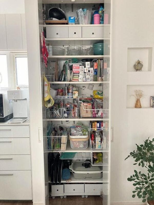 Full pantry shelves crowded with storage baskets and household items