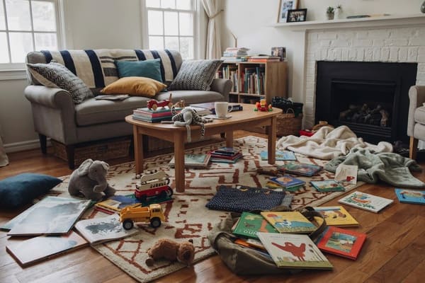 Living room floor with books toys and household belongings collecting around furniture