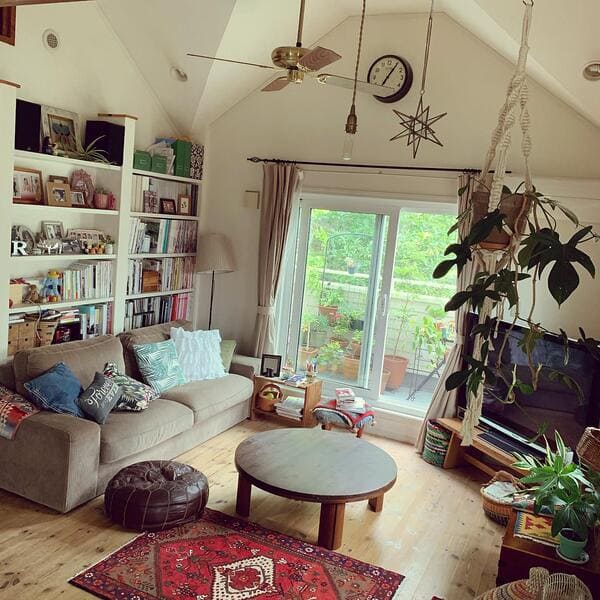 Living room crowded with books plants and decorative objects on shelves