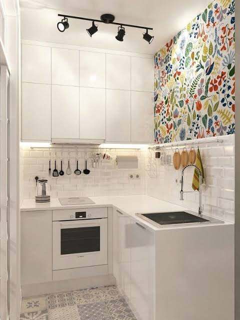 Tiny white corner kitchen with patterned wall decor, hanging utensils and track lighting