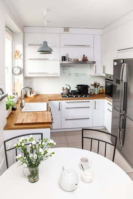 White corner kitchen with wood countertops, round dining table and stainless refrigerator
